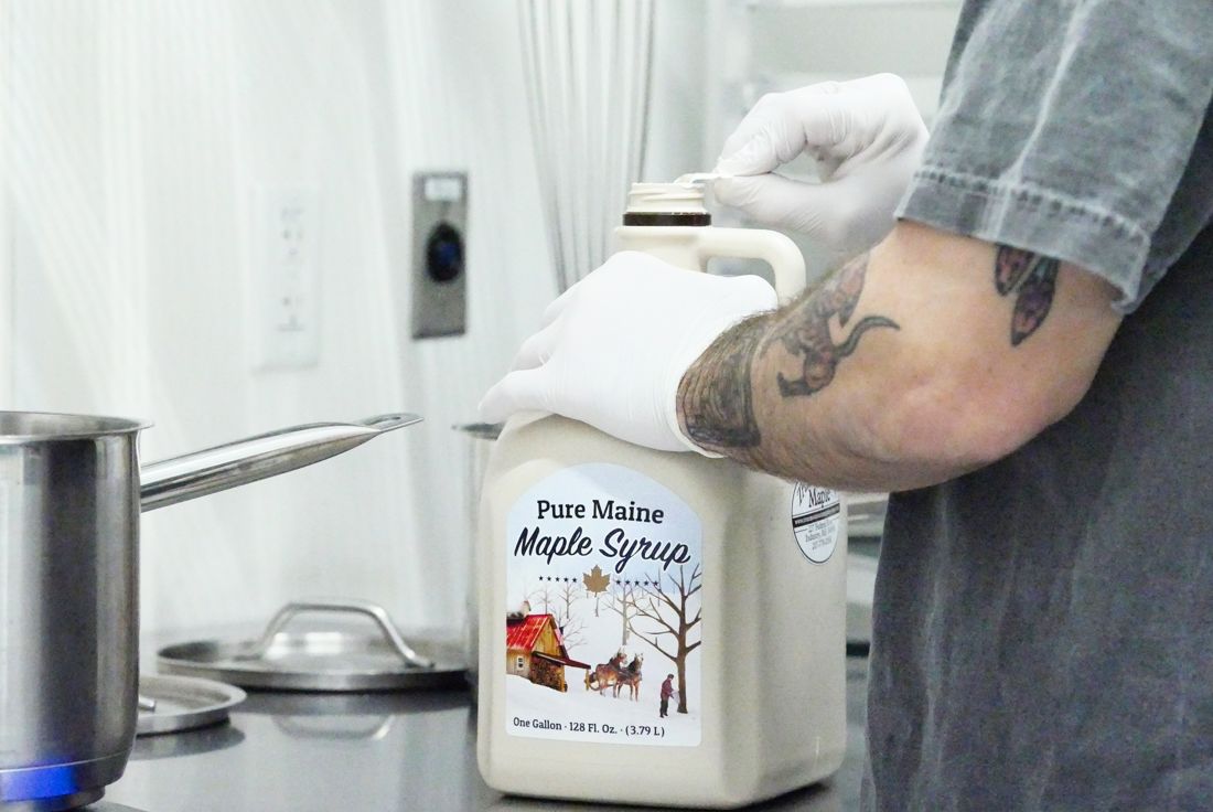 Kitchen crew opening a jug of Pure Maine maple syrup